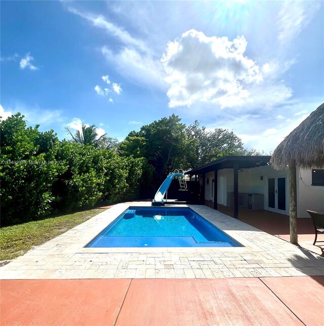 9130 SW 17th Ter, Miami, FL 33165 - swimming pool with a water slide, french doors, and a patio