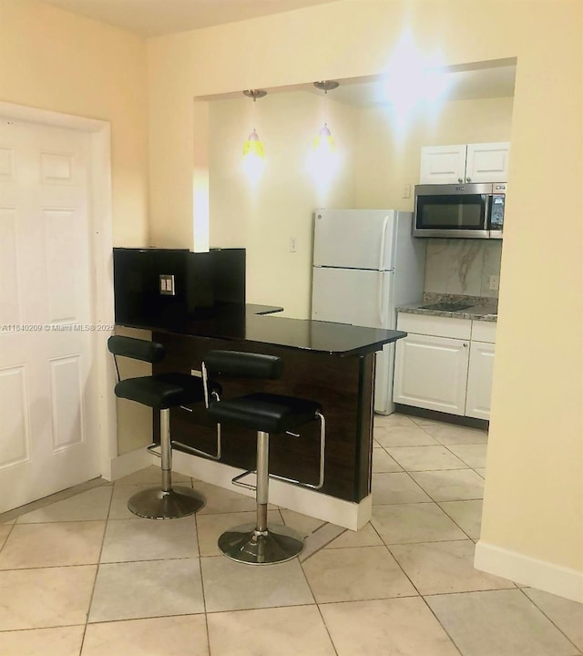 9130 SW 17th Ter, Miami, FL 33165 - kitchen featuring stainless steel microwave, freestanding refrigerator, white cabinets, and a peninsula