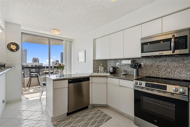 3530 Mystic Pointe Dr Unit 2014, Aventura, FL 33180 - kitchen with stainless steel appliances, floor to ceiling windows, backsplash, a peninsula, and white cabinetry