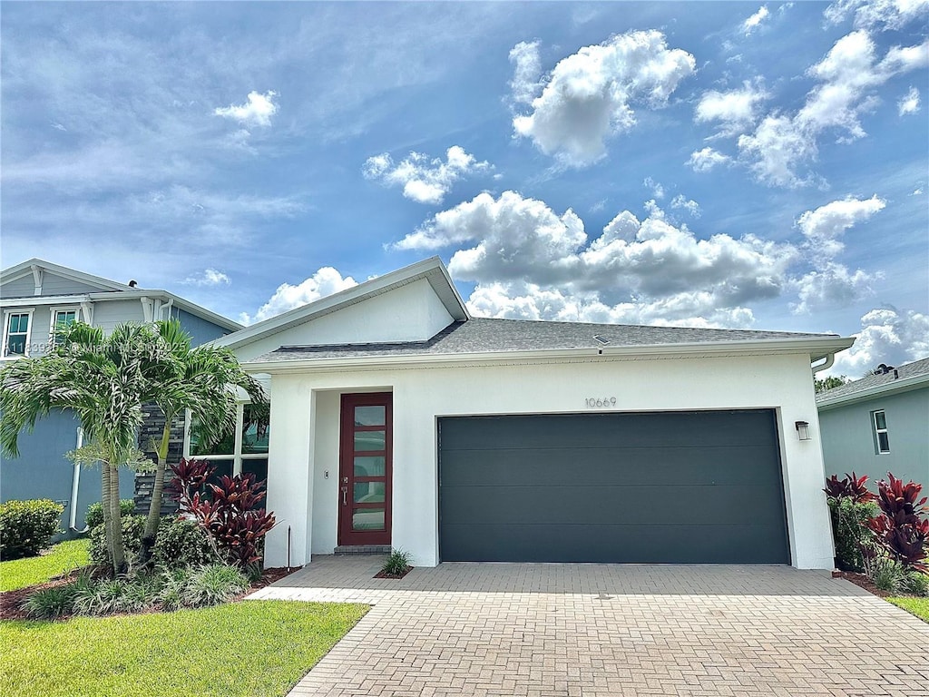 10669 SW Gloriana St, Port St Lucie, FL 34987 - view of front of home with stucco siding, an attached garage, and decorative driveway