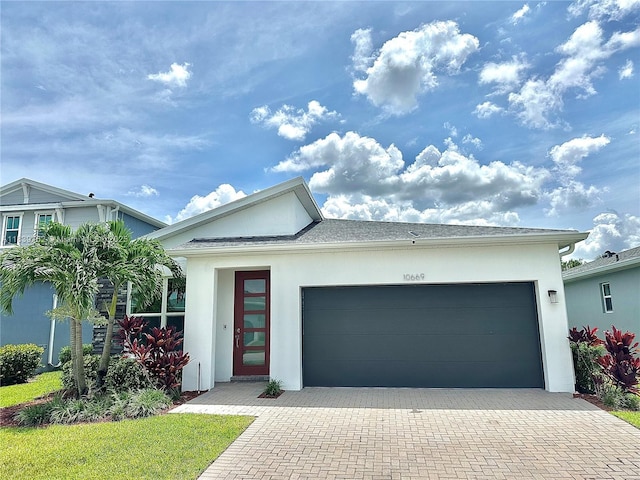 10669 SW Gloriana St, Port St Lucie, FL 34987 - view of front of home with stucco siding, an attached garage, and decorative driveway