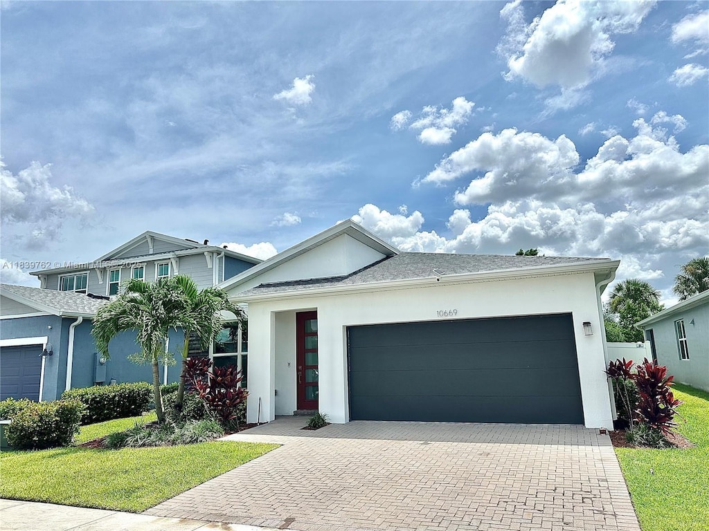 10669 SW Gloriana St, Port St Lucie, FL 34987 - view of front of property featuring stucco siding, decorative driveway, an attached garage, and a front yard