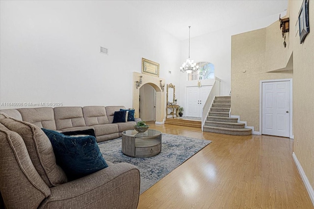 13063 NW 11th Ct, Sunrise, FL 33323 - living area featuring a chandelier, a high ceiling, wood finished floors, stairs, and arched walkways