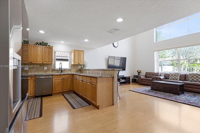 13063 NW 11th Ct, Sunrise, FL 33323 - kitchen featuring dishwasher, open floor plan, light wood-style floors, a peninsula, and a textured ceiling