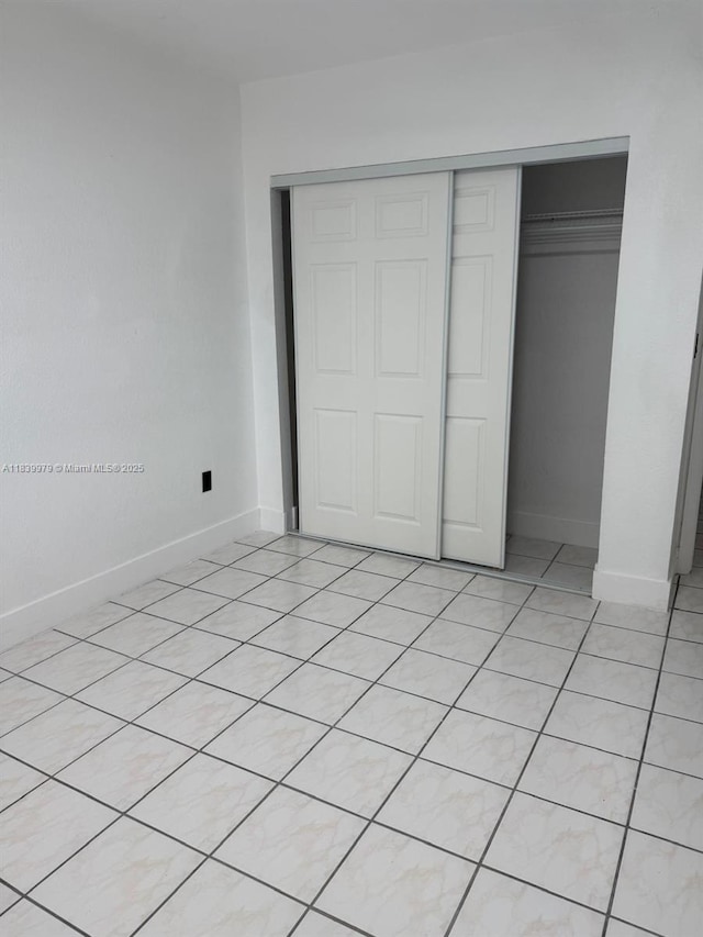 3860 W 11th Ln, Hialeah, FL 33012 - unfurnished bedroom featuring a closet and light tile patterned floors