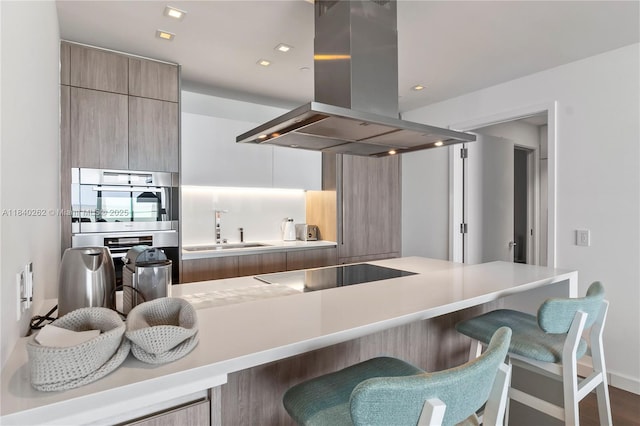 360 Ocean Dr Unit 704S, Key Biscayne, FL 33149 - kitchen featuring island exhaust hood, modern cabinets, a kitchen breakfast bar, black electric cooktop, and light countertops