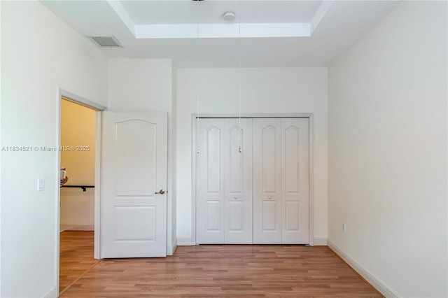 11647 NE 18th Dr Unit 11647, North Miami, FL 33181 - unfurnished bedroom featuring light wood-style flooring, a closet, and a tray ceiling