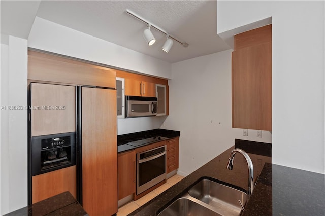 335 S Biscayne Blvd Unit 3410, Miami, FL 33131 - kitchen with appliances with stainless steel finishes, dark stone counters, rail lighting, and brown cabinetry