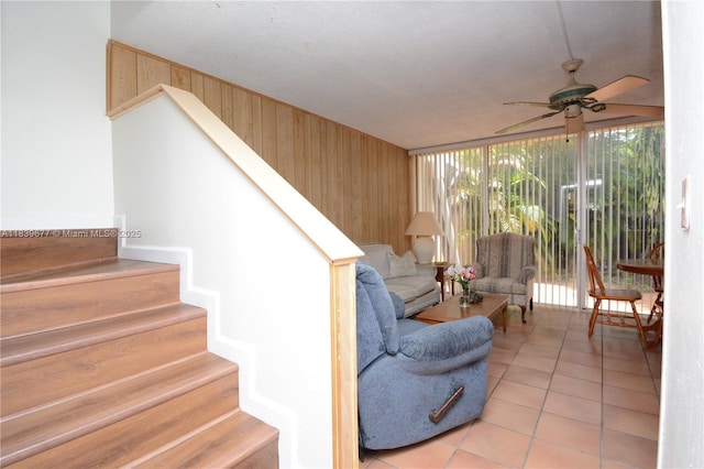 13935 SW 84th St Unit 905, Miami, FL 33183 - living room featuring a ceiling fan, stairs, wood walls, light tile patterned flooring, and expansive windows