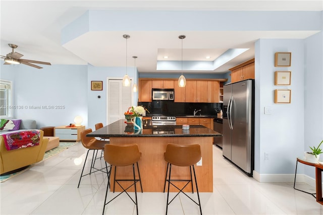 2919 Coconut Ave Unit 1, Miami, FL 33133 - kitchen with appliances with stainless steel finishes, ceiling fan, a kitchen island, a kitchen bar, and tasteful backsplash