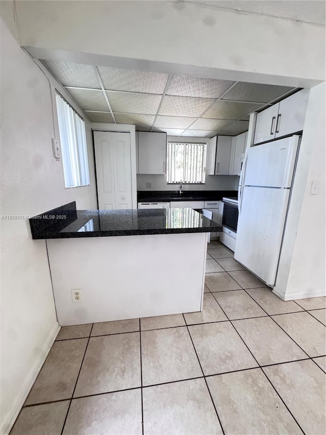 6900 SW 39th St Unit 208J, Davie, FL 33314 - kitchen featuring freestanding refrigerator, a peninsula, stove, a drop ceiling, and light tile patterned flooring