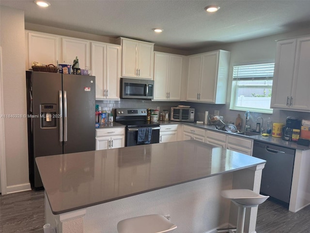 144 Taft Dr, Davenport, FL 33837 - kitchen featuring appliances with stainless steel finishes, dark wood-style floors, white cabinets, backsplash, and a breakfast bar area