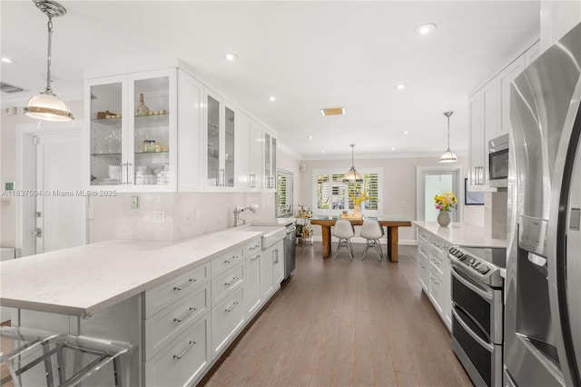 1261 San Miguel Ave, Coral Gables, FL 33134 - kitchen featuring appliances with stainless steel finishes, crown molding, white cabinetry, tasteful backsplash, and light stone countertops