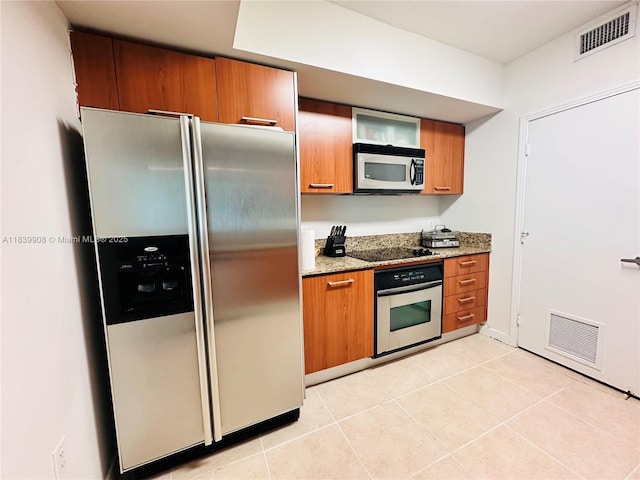 9066 SW 73rd Ct Unit 1409, Miami, FL 33156 - kitchen with stainless steel appliances, brown cabinets, light stone counters, and light tile patterned floors