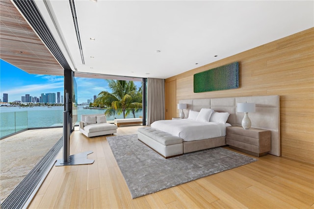 126 W San Marino Dr, Miami Beach, FL 33139 - bedroom with wooden walls, access to outside, a water view, wood finished floors, and expansive windows