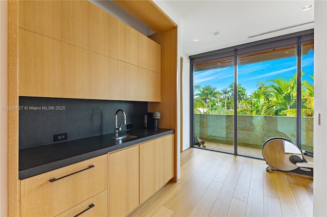 126 W San Marino Dr, Miami Beach, FL 33139 - kitchen featuring floor to ceiling windows, light brown cabinetry, light wood finished floors, dark countertops, and modern cabinets