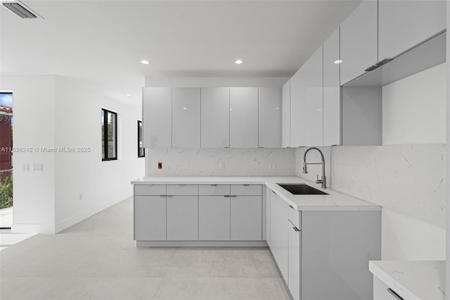 1271 NW 38th St, Miami, FL 33142 - kitchen featuring gray cabinetry, modern cabinets, recessed lighting, backsplash, and light stone counters