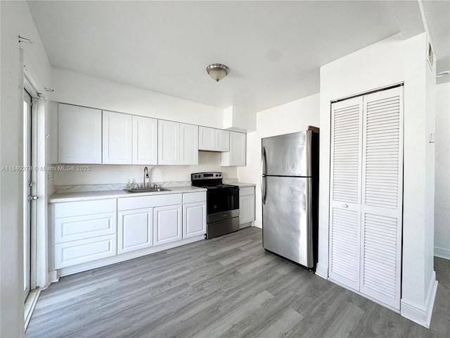 1130 NE 111th St, Biscayne Park, FL 33161 - kitchen with appliances with stainless steel finishes, light wood-style flooring, light countertops, and white cabinetry