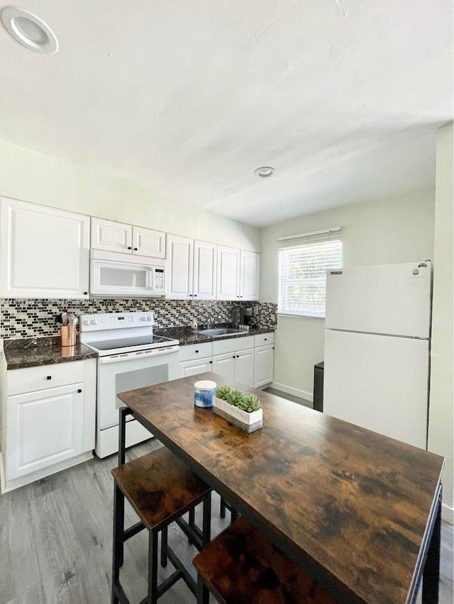 1130 NE 111th St, Biscayne Park, FL 33161 - kitchen featuring white appliances, dark countertops, backsplash, white cabinets, and light wood finished floors