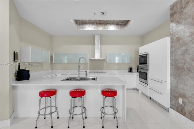 200 Sunny Isles Blvd Unit Th-404, Sunny Isles Beach, FL 33160 - kitchen featuring wall chimney exhaust hood, oven, built in microwave, a peninsula, and a breakfast bar area