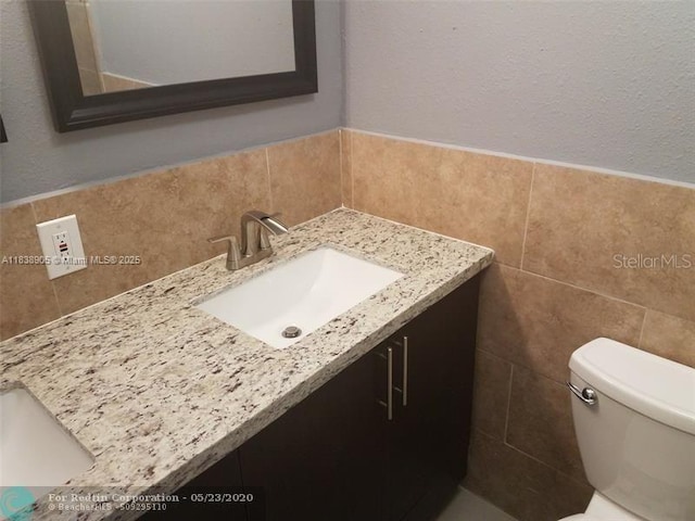 1610 S 22nd Ave, Hollywood, FL 33020 - half bath with tile walls, vanity, a textured wall, and a wainscoted wall