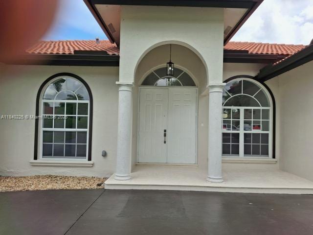 16961 SW 213th Ln, Miami, FL 33187 - view of exterior entry with stucco siding and a tiled roof