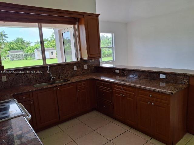 16961 SW 213th Ln, Miami, FL 33187 - kitchen with light tile patterned flooring, tasteful backsplash, a peninsula, and dark stone counters