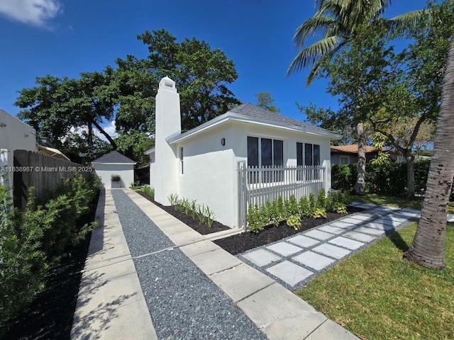 1923 NW 48th St, Miami, FL 33142 - view of front of home with stucco siding, a chimney, and a storage shed