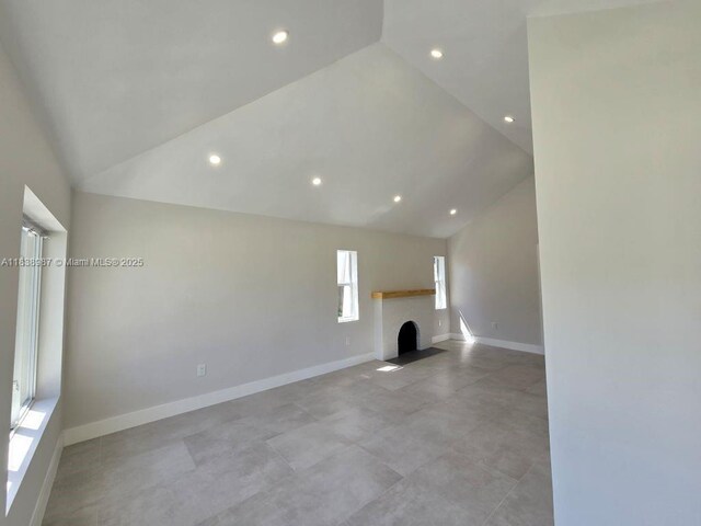 1923 NW 48th St, Miami, FL 33142 - unfurnished living room with vaulted ceiling, recessed lighting, and a fireplace with flush hearth