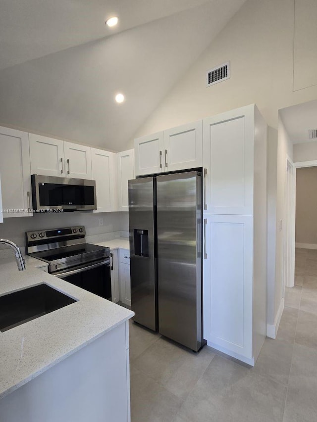 1923 NW 48th St, Miami, FL 33142 - kitchen with stainless steel appliances, light stone counters, white cabinets, recessed lighting, and high vaulted ceiling