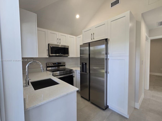 1923 NW 48th St, Miami, FL 33142 - kitchen with appliances with stainless steel finishes, light stone countertops, white cabinetry, light tile patterned floors, and vaulted ceiling