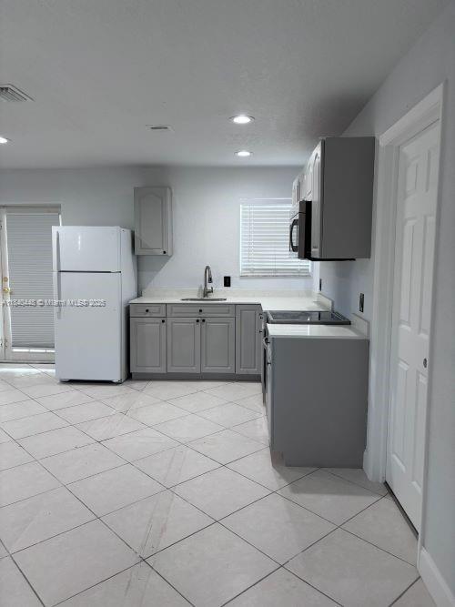 433 SW 28th Ave, Fort Lauderdale, FL 33312 - kitchen featuring freestanding refrigerator, gray cabinets, light countertops, light tile patterned floors, and recessed lighting