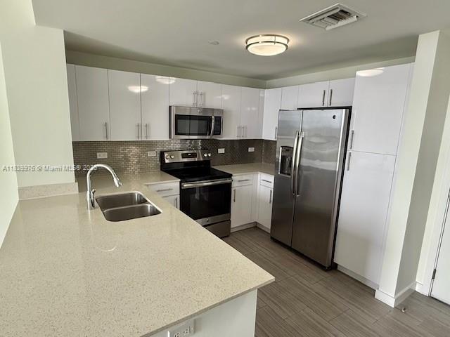 1776 SW Polk St Unit 1412, Hollywood, FL 33020 - kitchen featuring appliances with stainless steel finishes, tasteful backsplash, light countertops, and white cabinets