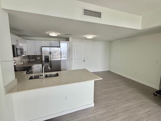 1776 SW Polk St Unit 1412, Hollywood, FL 33020 - kitchen featuring stainless steel appliances, a peninsula, decorative backsplash, white cabinetry, and light wood-type flooring
