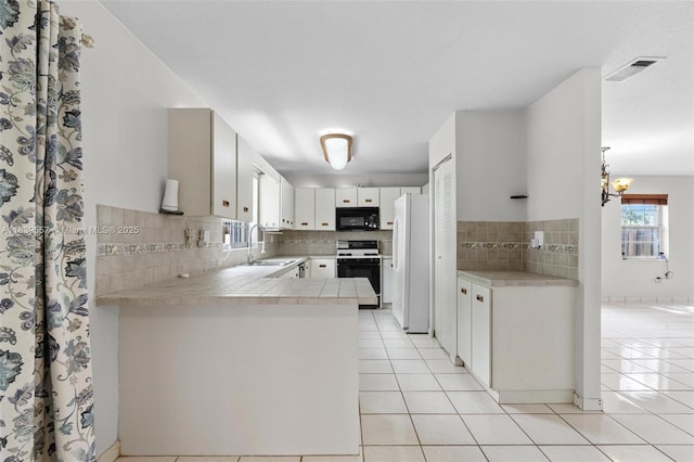 7767 NW 187th Ter, Miami, FL 33015 - kitchen featuring electric range, black microwave, freestanding refrigerator, and light tile patterned floors
