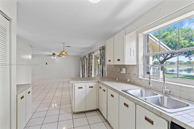 7767 NW 187th Ter, Miami, FL 33015 - kitchen with white cabinets, a peninsula, a ceiling fan, backsplash, and light tile patterned floors