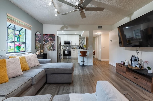 7625 NW 79th Ave Unit 101, Tamarac, FL 33321 - living area with a textured ceiling, light wood-style flooring, rail lighting, and ceiling fan
