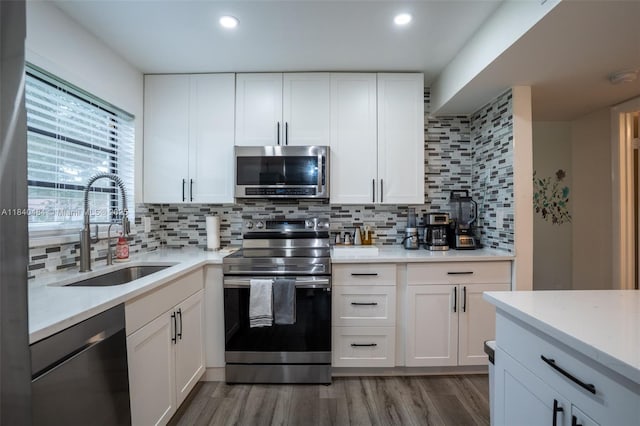 7625 NW 79th Ave Unit 101, Tamarac, FL 33321 - kitchen featuring appliances with stainless steel finishes, light wood finished floors, tasteful backsplash, white cabinetry, and recessed lighting
