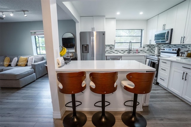 7625 NW 79th Ave Unit 101, Tamarac, FL 33321 - kitchen featuring appliances with stainless steel finishes, a kitchen bar, tasteful backsplash, open floor plan, and recessed lighting