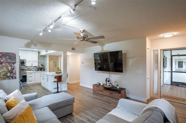 7625 NW 79th Ave Unit 101, Tamarac, FL 33321 - living area featuring light wood-style flooring, a textured ceiling, ceiling fan, and track lighting