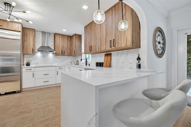 5701 SW 33rd St, Miami, FL 33155 - kitchen featuring built in refrigerator, brown cabinetry, wall chimney range hood, a peninsula, and backsplash