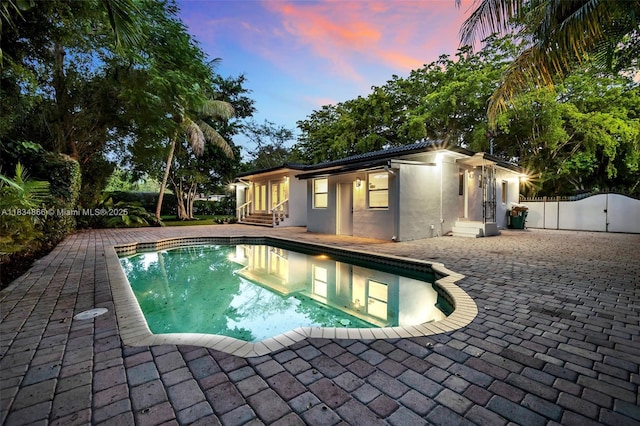 5701 SW 33rd St, Miami, FL 33155 - pool at dusk with a patio area, a gate, and entry steps