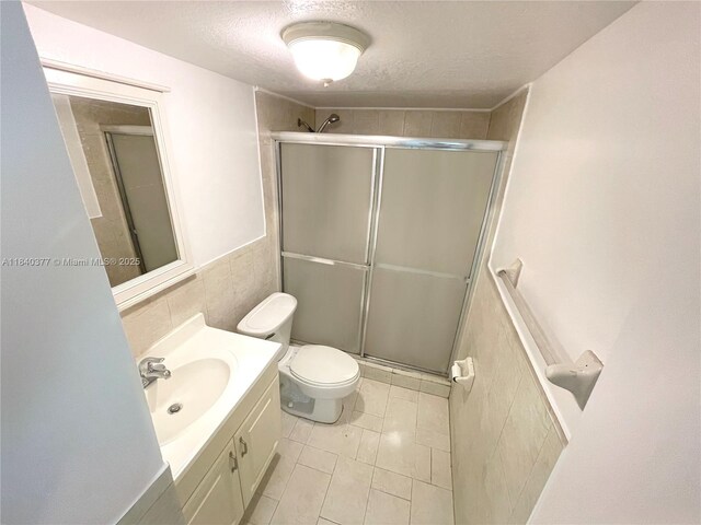 1725 SW 131st Place Cir S, Miami, FL 33175 - full bath featuring vanity, tile walls, a shower with door, a textured ceiling, and wainscoting