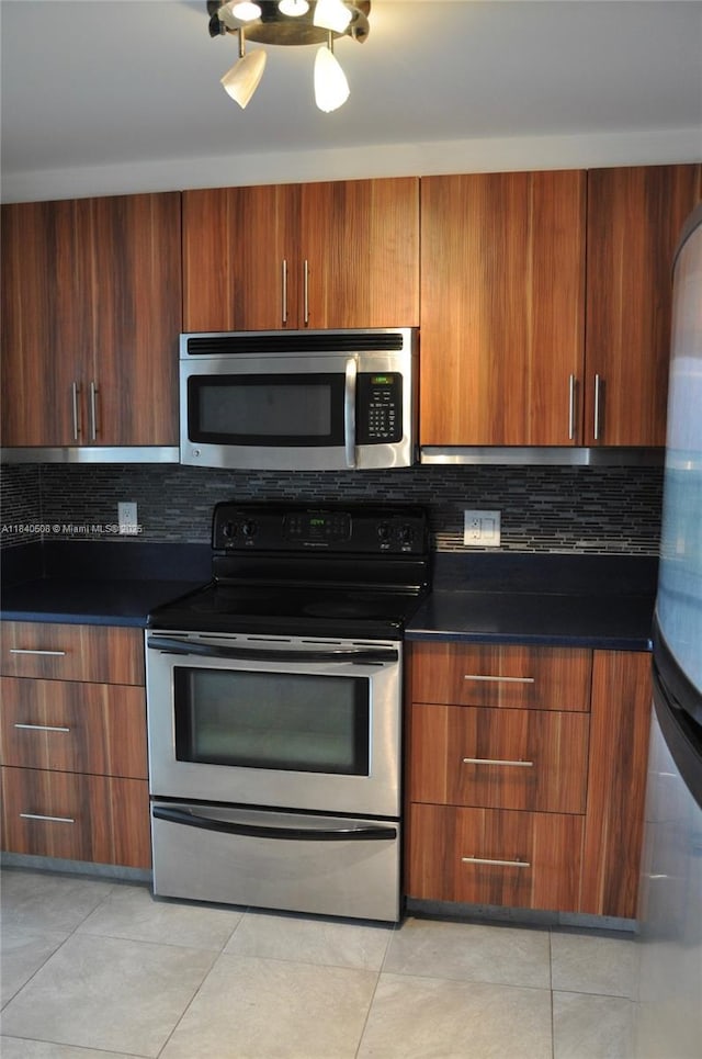 13499 Biscayne Blvd Unit 1011, North Miami, FL 33181 - kitchen featuring appliances with stainless steel finishes, tasteful backsplash, dark countertops, and light tile patterned flooring