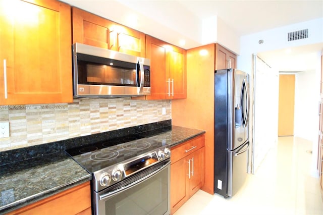 20185 E Country Club Dr Unit 1105, Aventura, FL 33180 - kitchen featuring stainless steel appliances, dark stone counters, brown cabinetry, and decorative backsplash