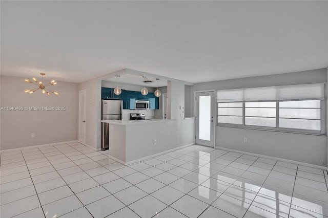 1100 11th St Unit 204, Miami Beach, FL 33139 - kitchen with stainless steel appliances, a chandelier, blue cabinetry, a peninsula, and light tile patterned flooring