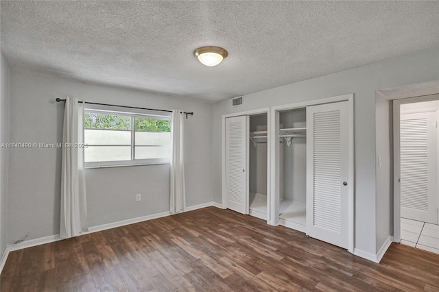 1100 11th St Unit 204, Miami Beach, FL 33139 - unfurnished bedroom featuring wood finished floors, two closets, and a textured ceiling