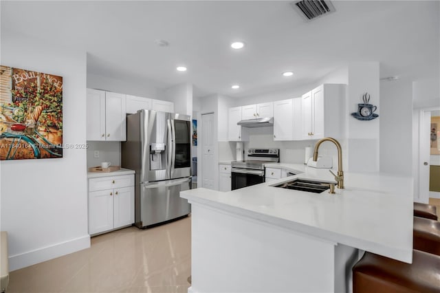 1204 Bayview Cir, Weston, FL 33326 - kitchen featuring a peninsula, appliances with stainless steel finishes, light countertops, white cabinets, and a kitchen breakfast bar