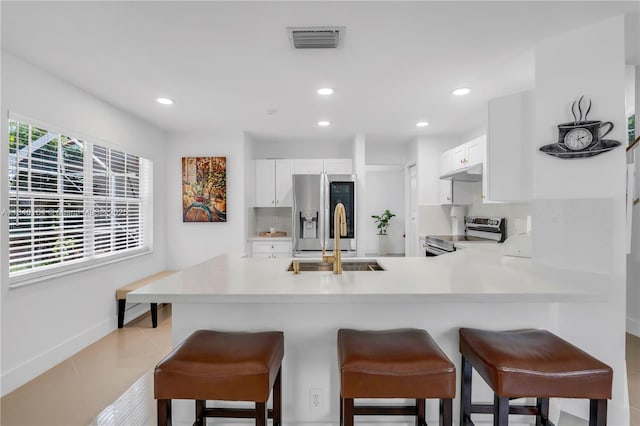 1204 Bayview Cir, Weston, FL 33326 - kitchen with a peninsula, stainless steel appliances, light countertops, white cabinets, and a breakfast bar