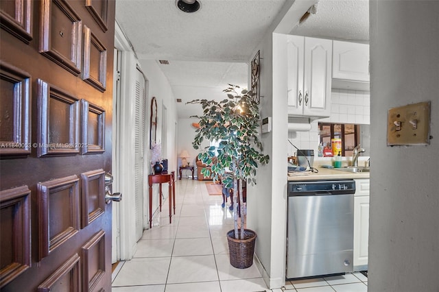 9530 W Daffodil Ln, Miramar, FL 33025 - kitchen featuring stainless steel dishwasher, a textured ceiling, light tile patterned floors, white cabinets, and light countertops